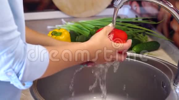 厨房里一个年轻女孩在家洗红椒的特写镜头视频的预览图