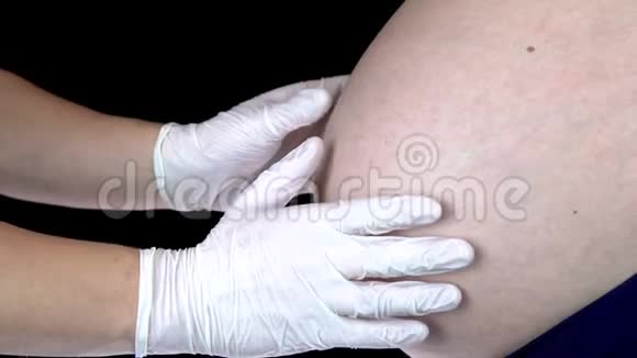 医生触摸孕妇的腹部并显示出类似的情况有一个大肚子的年轻女人被医生检查过视频的预览图