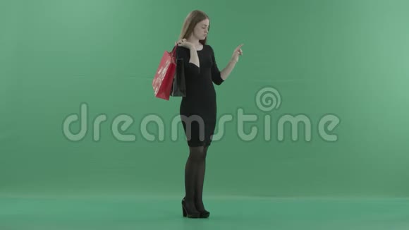 美丽的女人穿着黑色的小连衣裙手里拿着购物袋在数字屏幕上滚动她站在右边视频的预览图