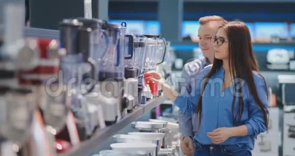 一对年轻夫妇在电器商店为他们的厨房挑选搅拌机视频的预览图