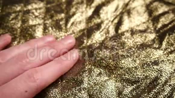 一个女人手滑过光滑的合成金色尼龙和涤纶织物视频的预览图