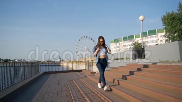 一个年轻的女孩走在城市海湾的堤岸上视频的预览图