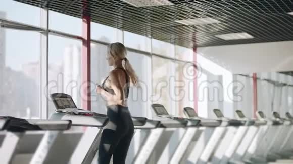健身妇女在健身房跑步机上跑步有心脏训练的漂亮女孩视频的预览图