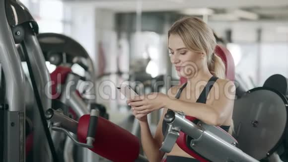 健身妇女在体育健身馆用手机放松视频的预览图