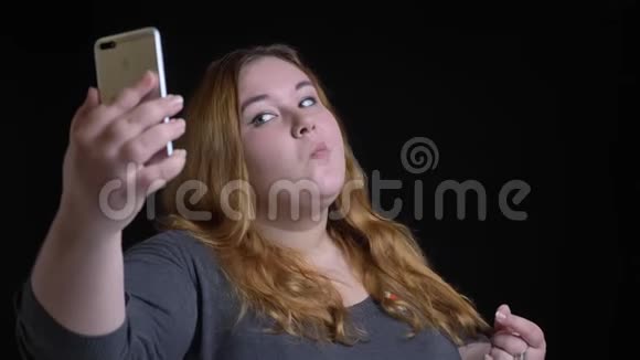 一位年轻的超重白种人女性的特写镜头她的头发是金色的深色头发在电话里自拍然后摆姿势视频的预览图
