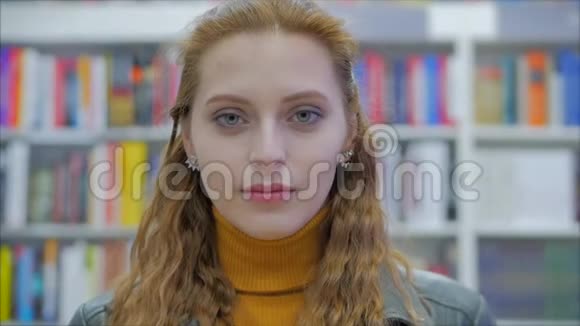 一幅幸福美丽的女学生的特写镜头微笑着看着站在大学图书馆的镜头视频的预览图