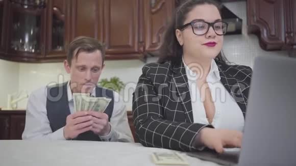 描绘年轻的自信的丰满的女人在桌子上拿着笔记本电脑工作一个胆小的年轻人要求更多的钱视频的预览图