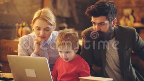 幸福的家庭一起看电影带笔记本电脑的小孩妈妈和爸爸用笔记本电脑看动画片视频的预览图