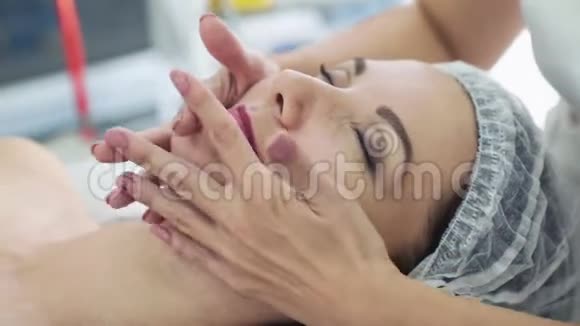 美容院美容师的双手合拢用闭着眼睛给女人做面部按摩视频的预览图