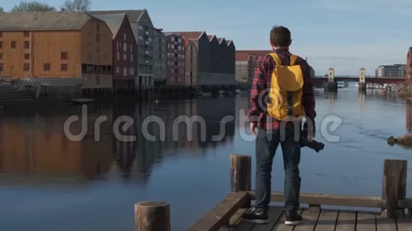 迷人的年轻英俊的游客带着黄色的背包在市中心散步拍照慢动作视频的预览图
