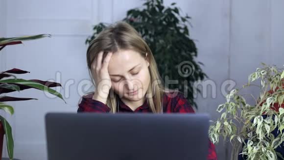 年轻女子厌倦了在笔记本电脑上工作揉着太阳穴视频的预览图
