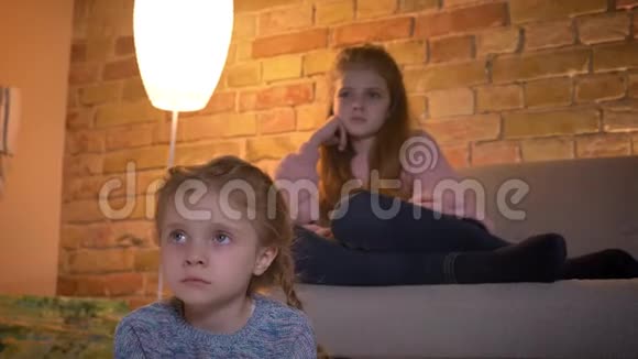 特写肖像两个高加索女孩在舒适的家庭氛围中专心看电影视频的预览图