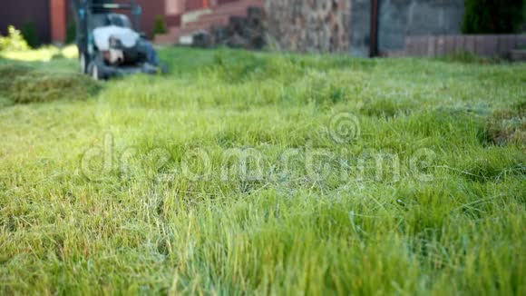 男子园丁割草机割草机阳光明媚的一天楼下的照相机视频的预览图
