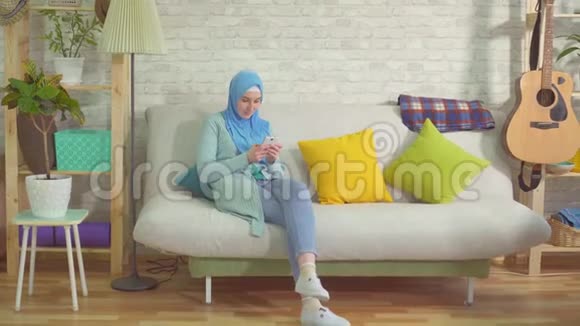戴着头巾的漂亮穆斯林女人学会了用智能手机和舞蹈获胜视频的预览图