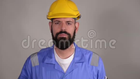 戴着头盔的长胡子工人在电话里和灰色背景的人交谈视频的预览图