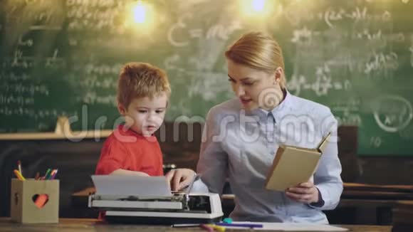 母亲和儿子坐在桌子旁正在教室里用一台旧打字机打印母亲和儿子视频的预览图