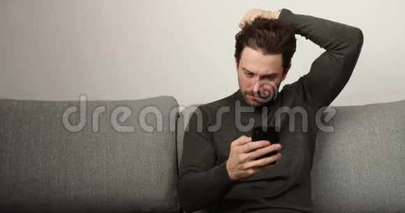 男人在电话里聊天时尚的发型和漂亮的视野坐在客厅沙发上的男人视频的预览图