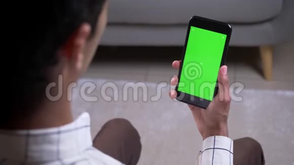 特写后景拍摄男性有视频通话手拿手机绿色屏幕在室内视频的预览图