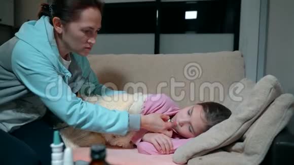 一个发烧的小女孩躺在沙发上母亲在的帮助下测量女儿的体温视频的预览图