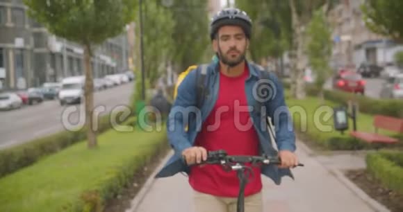 带背包的成年白人送货员在户外公园骑脚踏车的特写照片视频的预览图
