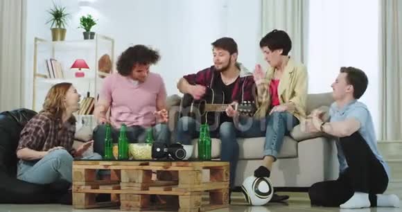 在现代宽敞的客厅里一群朋友一起在沙发上弹吉他唱歌视频的预览图