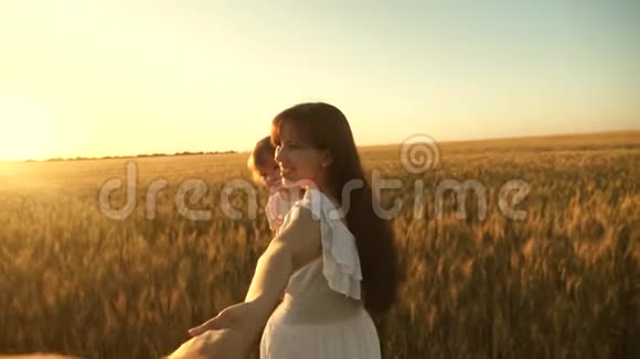 幸福的一家人牵着手跑过田野美丽的女孩带着女儿带着麦子走在田野上抱着她视频的预览图
