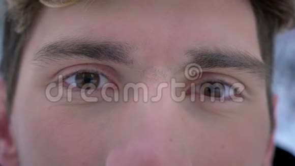 年轻迷人的白种人男性面部特写镜头棕色眼睛张开直视镜头视频的预览图