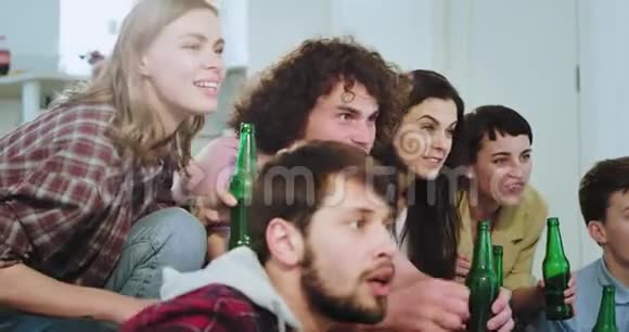 在一个现代化的家庭中一群多民族的朋友观看了一场情绪激动的足球赛他们首先高兴地庆祝视频的预览图