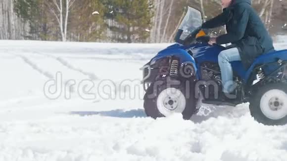 日光下的冬林寒冷的天气一个成年人骑着蓝色的大雪车视频的预览图
