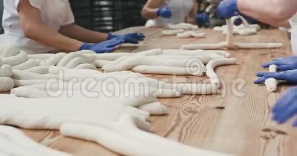 在一个大的烘焙行业两个面包师带着蓝色手套准备面团揉面团准备面包4k视频的预览图