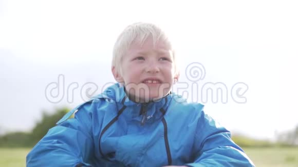 可爱的男孩金发坐在草地上悲伤视频的预览图