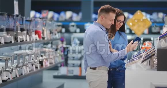 幸福的一对夫妻站在柜台前穿着便服的手机选择了一款新的智能手机视频的预览图