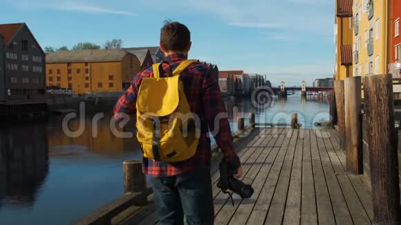 迷人的年轻英俊的游客带着黄色的背包在市中心散步拍照慢动作视频的预览图