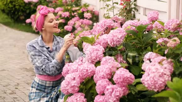 女孩喷花绣球花幸福的年轻女子园丁在植物上喷水的肖像爱好概念青年视频的预览图