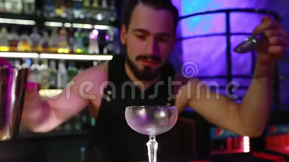 大胡子的酒保把准备好的鸡尾酒倒入玻璃杯里视频的预览图