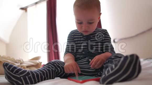 一个婴儿点击智能手机的屏幕坐在床上慢动作视频的预览图