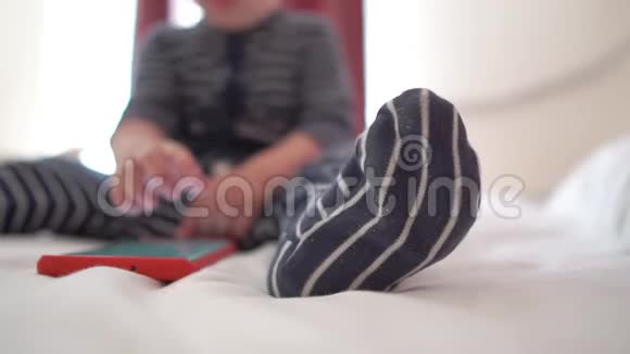 一个孩子点击智能手机的屏幕坐在床上慢动作视频的预览图