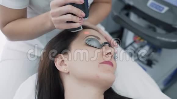 特写美容医生在诊所对年轻女性面部做头发激光去除手术慢动作视频的预览图