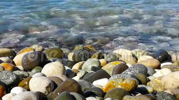 阳光明媚的夏日卵石和海水近景视频的预览图