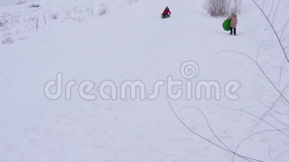 在冬天少女们坐着雪碟从高高的雪山上骑马孩子们在新鲜空气中冬天的游戏快乐的孩子视频的预览图