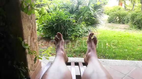 男人的腿在夏天躺在甲板椅上放松视频的预览图
