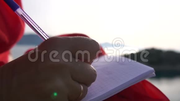 一个女人在日出时慢动作地在笔记本上写字她的双手紧闭视频的预览图