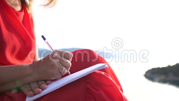 一个女人在日出时慢动作地在笔记本上写字她的双手紧闭视频的预览图