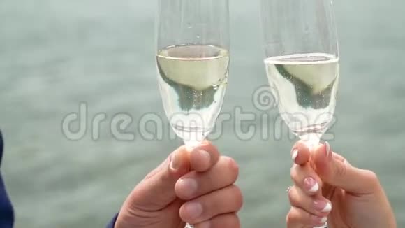 男人和女人在流动的水背景下闪烁着的香槟酒杯戴上眼镜和手视频的预览图