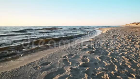 日落时的波罗的海沙滩柔软的海浪远走高飞的人视频的预览图