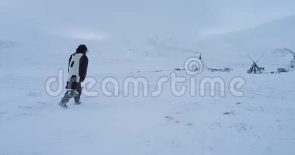 在北极行走的无人机中间他穿着传统的衣服穿过雪地来到蒙古包视频的预览图