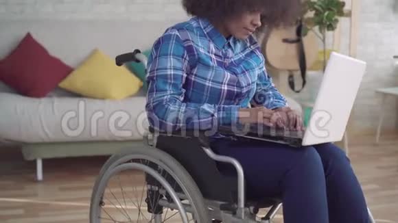 肖像残疾非裔美国妇女头发是非洲的坐轮椅使用笔记本电脑视频的预览图