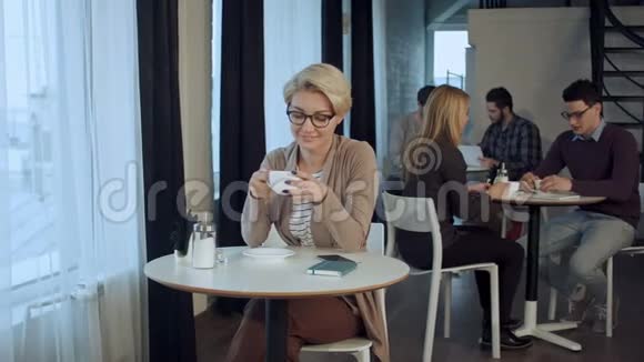 年轻漂亮的女性一边喝茶一边沉思地看着咖啡店的橱窗一边欣赏她的肖像视频的预览图