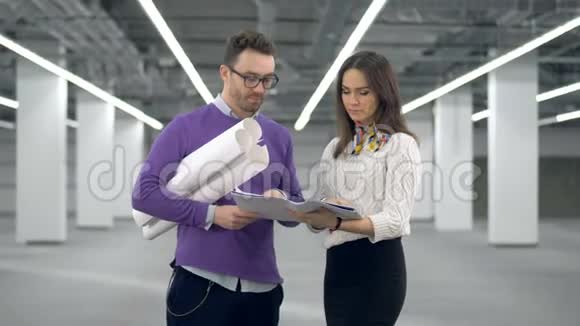 男建筑师拿着图纸和女同事谈话视频的预览图