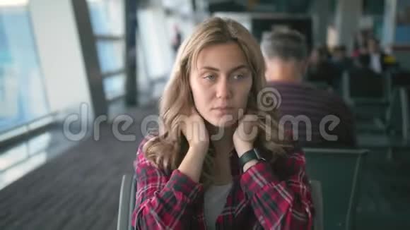 动作缓慢疲惫的年轻美丽的女孩穿着红色格子衬衫被脖子牵着坐在出发区的视频的预览图